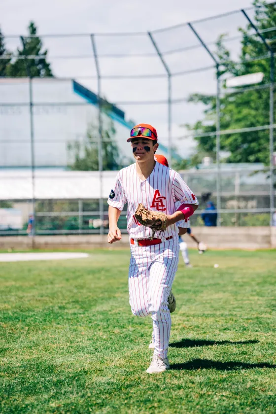An Abbotsford Cardinals player jogging in and laughing after a play.
