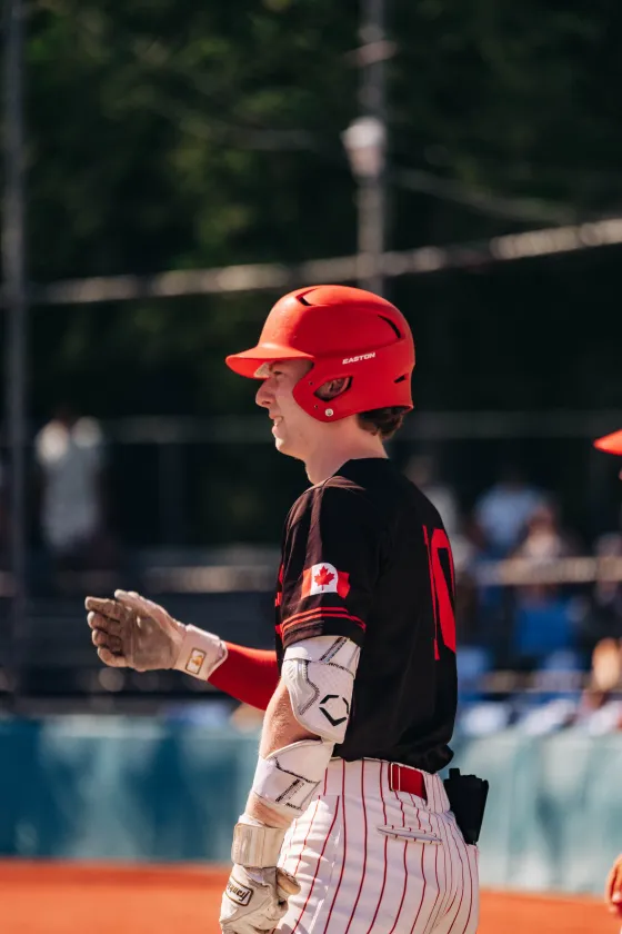 A young Abbotsford Cardinals player claps in a red helmet.