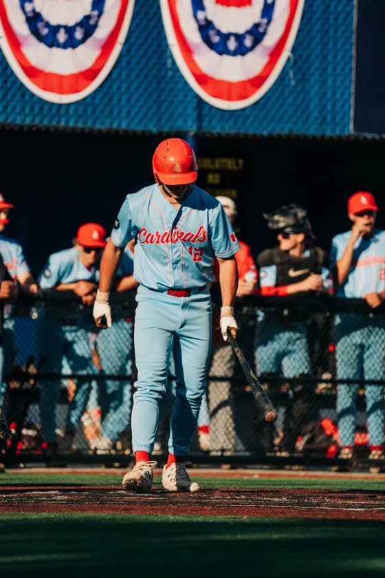An Abbotsford Cardinals player waits in the dugout, bat down, before his at-bat.
