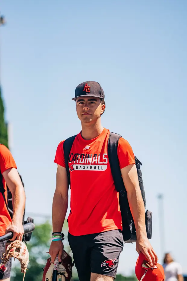 A Cardinals player arrives at the ballpark carrying his gear.