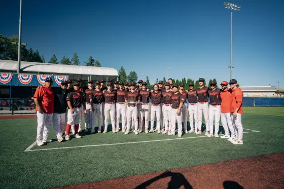 The 2026 Cardinals and their coaching staff lined up on the field with the qualifier finalists trophy.
