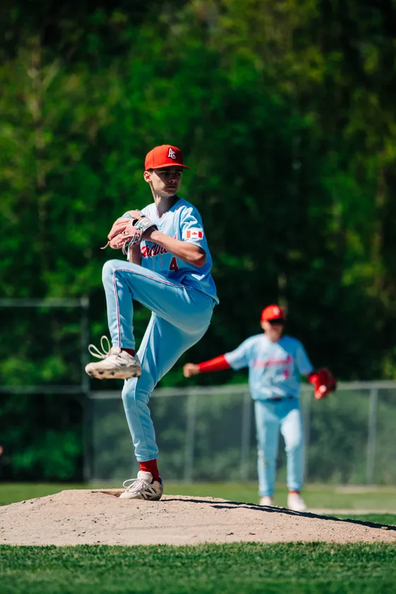 A Cardinals pitcher lifts his leg to deliver during a home game.