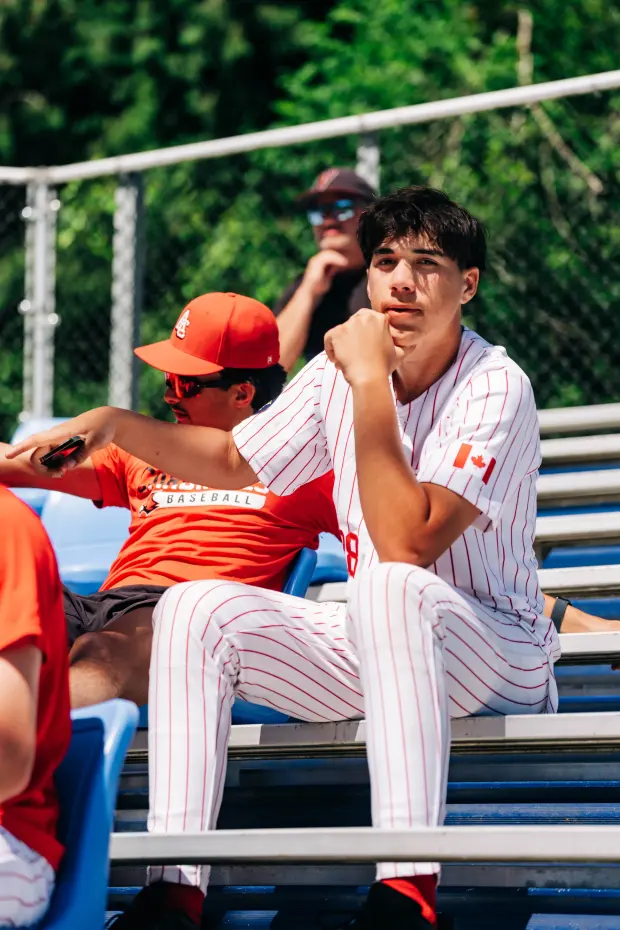 Two Cardinals sit together on the dugout bench, mid-conversation.