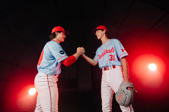 Two Abbotsford Cardinals players shake hands under studio light.