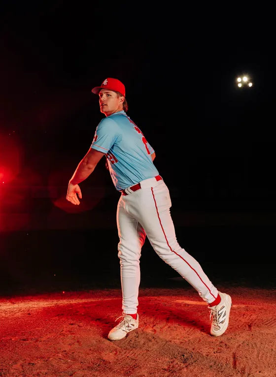 An Abbotsford Cardinals pitcher throws in a red-lit night portrait.