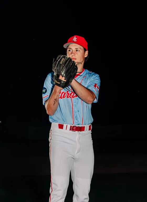 An Abbotsford Cardinals pitcher looks in over his glove in a night portrait.