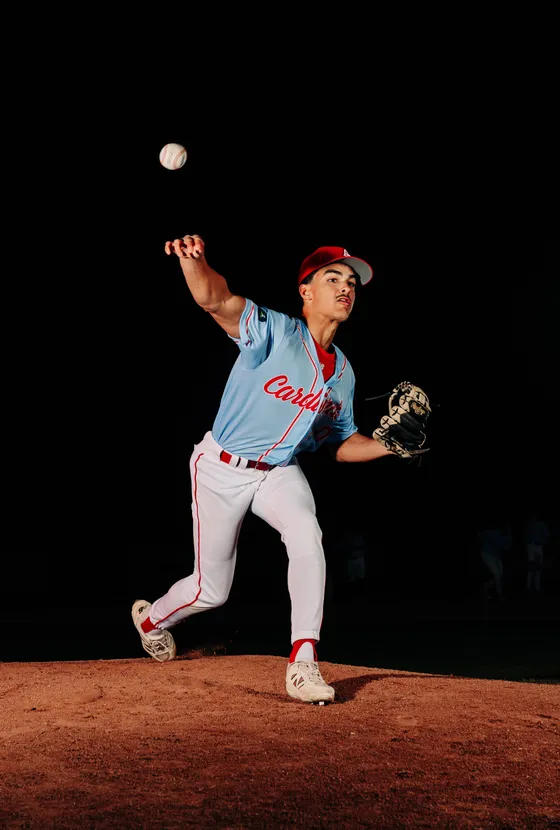 An Abbotsford Cardinals pitcher releases a pitch in a night portrait.