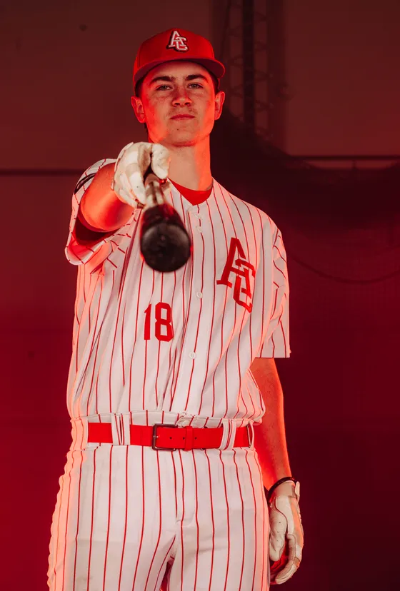 An Abbotsford Cardinals player points his bat toward the camera in a studio portrait.