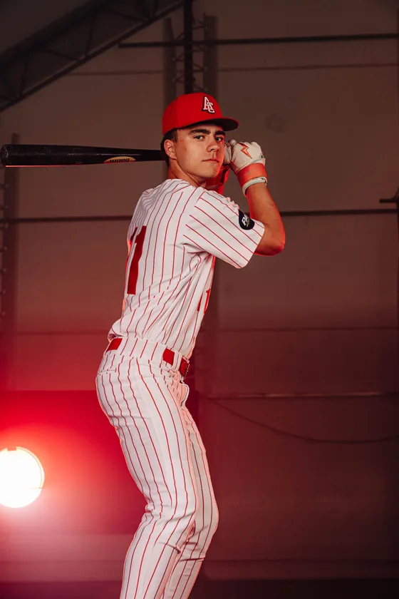 An Abbotsford Cardinals hitter poses with a bat under red studio light.